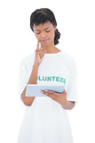 Pensive black haired volunteer using a tablet pc