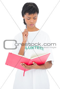Pensive black haired volunteer looking at a notebook