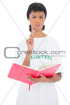 Frowning black haired volunteer holding a notebook