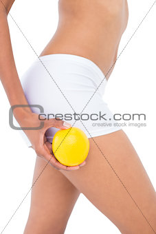 Close up of a fit woman holding an orange