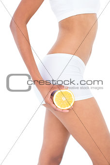 Close up of a fit woman presenting half an orange