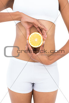 Close up of a fit model holding half an orange