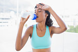 Exhausted fit woman drinking a bottle of water