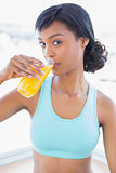 Thoughtful fit woman drinking a glass of orange juice