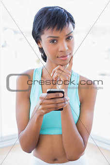 Thoughtful black haired woman holding a mobile phone