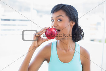 Charming black haired woman eating an apple