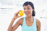 Surprised black haired woman holding an orange