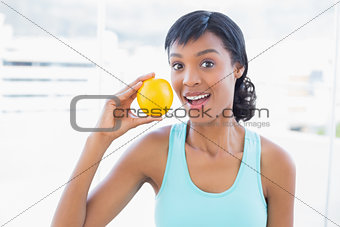 Surprised black haired woman holding an orange