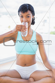 Calm black haired woman drinking a glass of water