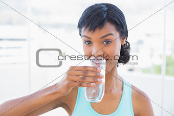 Charming black haired woman drinking a glass of water