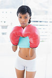 Frowning black haired woman wearing boxing gloves