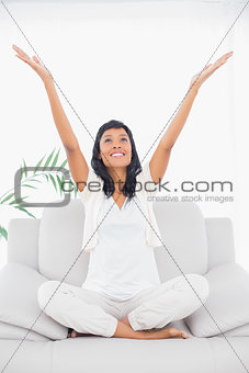 Cheerful black haired woman in white clothes raising her arms
