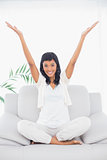 Pleased black haired woman in white clothes raising her arms