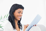 Smiling black haired woman in white clothes typing on a tablet pc