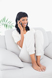 Amused black haired woman in white clothes phone calling