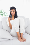 Happy black haired woman in white clothes typing on her mobile phone