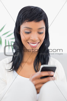 Stylish black haired woman in white clothes holding a mobile phone