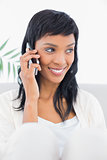 Attentive black haired woman in white clothes calling someone with her mobile phone