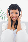 Calm black haired woman in white clothes listening to music