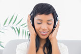 Dreamy black haired woman in white clothes listening to music