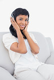 Peaceful black haired woman in white clothes listening to music