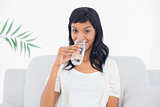 Seductive black haired woman in white clothes drinking water