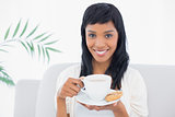 Calm black haired woman in white clothes drinking coffee
