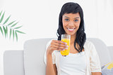 Lovely black haired woman in white clothes drinking orange juice