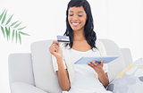Delighted black haired woman buying online with her tablet pc