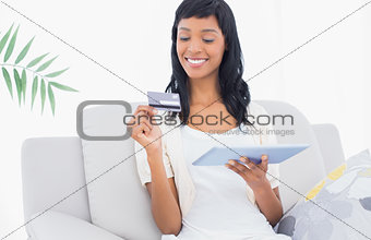 Delighted black haired woman buying online with her tablet pc