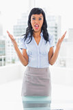 Irritated businesswoman looking at camera and raising her arms