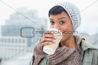 Happy young model in winter clothes enjoying coffee