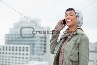 Laughing young model in winter clothes answering her phone