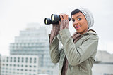 Amazed young model in winter clothes holding binoculars