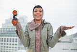 Pleased young model in winter clothes holding binoculars