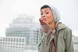 Attractive young model in winter clothes blowing a kiss to the camera