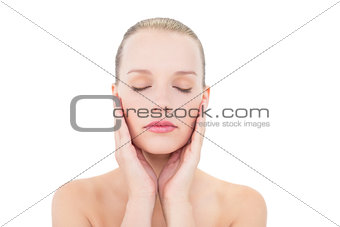 Pretty blonde model holding her cheeks with eyes closed