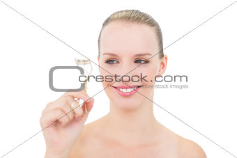 Pleased pretty blonde model looking at eyelash curler