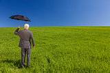 Businessman In A Green Field With An Umbrella