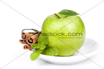 A Ripe Green Apple with mint and cinnamon on plate