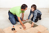 Father and son laying ceramic floor tiles
