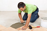 Man laying floor tiles - spreading the adhesive