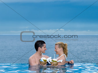 couple lovers swimming pool  seaside drinking coconut milk