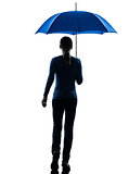woman rear view walking holding umbrella silhouette