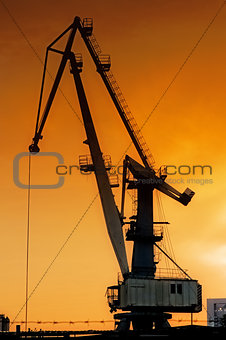 Silhouette of harbor crane at sunrise.