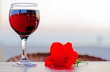 Glass of red wine with a flower at sunset.