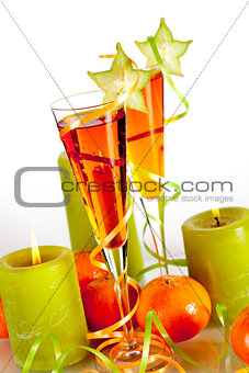 Two orange alcohol cocktails with mandarines and light candles