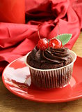 Chocolate Cupcake with cherries and cream on a red plate