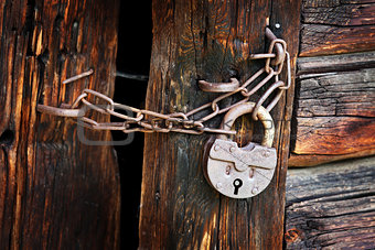 Old rusty padlock on rural wooden gate