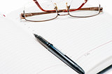 Opened diary, pen and glasses